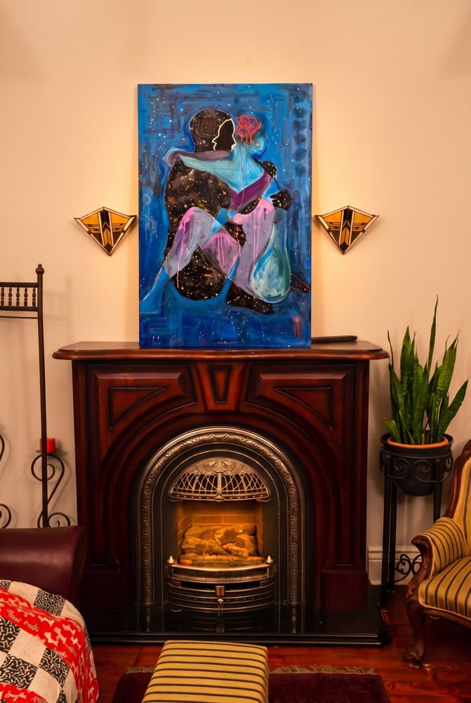 The Knot, a 48 by 30 inch HUMANMINK canvas of a seated figure on a blue ground, hung above a fireplace